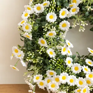 Close-up of white artificial daisy flowers and green foliage on decorative Easter wreath.