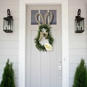 Green boxwood bunny wreath with burlap ears hanging on a front door for Easter decor