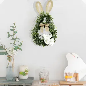 Green leaf Easter bunny wreath with burlap ears and white flowers in a home setting