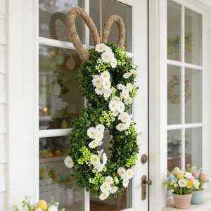 Detailed view of an Easter bunny wreath with green leaves and daisies hanging on a white door