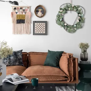 Artificial Easter wreath with eucalyptus leaves and speckled eggs hung in a cozy living room.