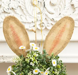 Detailed view of Easter bunny ears decoration with artificial daisies and greenery.