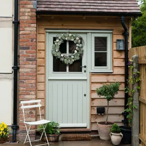 Elegant artificial Easter wreath with eucalyptus leaves on a rustic garden door.