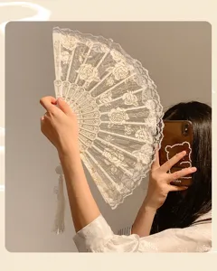 Detailed shot of white lace folding hand fan with rose floral pattern and elegant tassel decor.