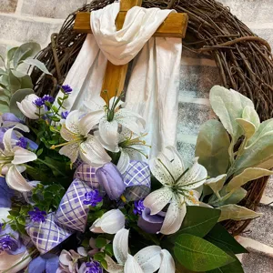 Detail view of an Easter cross wreath featuring white lilies and purple ribbon
