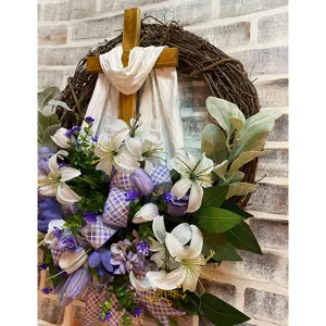 Detailed view of Easter wreath with wooden cross, white lilies and purple tulips.