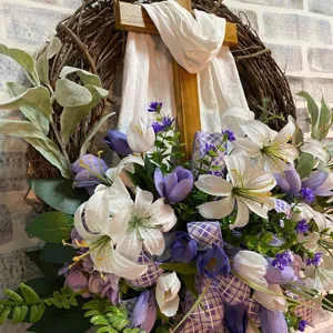 Detailed view of an Easter wreath with a wooden cross and white lilies