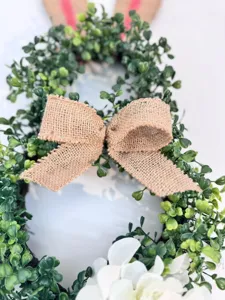 Detailaufnahme eines Osterhasenkranzes mit Juteschleife und grünen Buchsbaumblättern