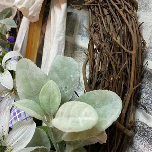 Close-up detail of Easter cross wreath with rustic grapevines and velvet green leaves