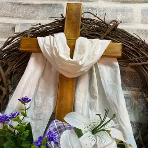 Detailed close-up view of an Easter cross wreath featuring white fabric drape and spring lilies