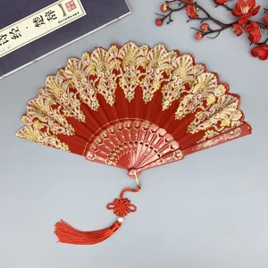 Eventail chinois avec dentelle rouge et or, baleines sculptées et pompon élégant.
