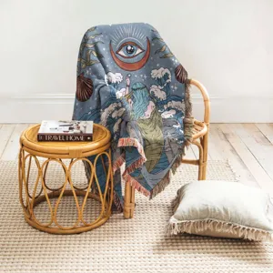 Artistic bohemian woven throw blanket with mystical ocean design on a rattan chair