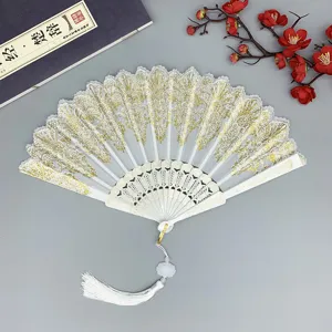 Éventail pliant de style chinois avec motif en dentelle dorée et pompon blanc élégant.