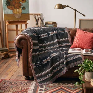 Detail view of a Bohemian woven blanket with geometric patterns and fringe on a sofa.