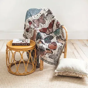 Gewebte Decke mit Schmetterlingsmuster auf einem Rattanstuhl in gemütlicher Umgebung.
