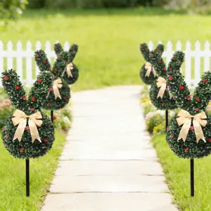 Decorative artificial boxwood bunny topiaries with gold bows lining a garden path.