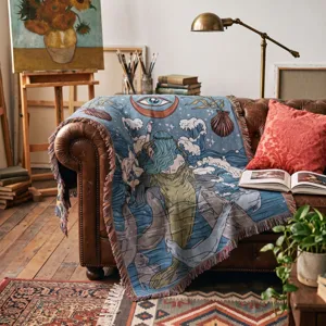 Intricate woven mermaid throw blanket with fringe tassels styled on a vintage leather sofa