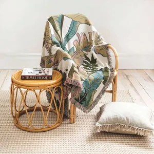 Close-up of bohemian woven blanket with tropical leaf pattern draped over a chair