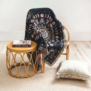 Couverture tissée bohème avec phases de lune et franges sur chaise en rotin