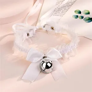 Détail de collier ras du cou en dentelle blanche avec nœud mignon et cloche argentée.