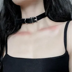 Primo piano di un elegante girocollo choker nero in pelle con fibbia e anello metallico.