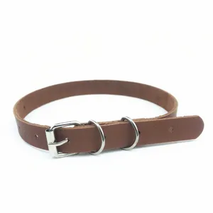 Dettaglio di un collare choker in pelle marrone con fibbia e anelli in metallo argentato, primo piano