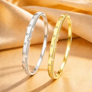 Close-up of elegant dual-tone silver and gold paved diamond bangles on satin fabric.