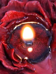 Primo piano dettagliato di una candela profumata artigianale rossa peonia con cera dorata.