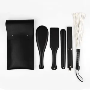 Detailed view of black leather BDSM restraint set featuring various paddles, whips and bag.