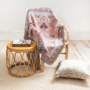 Close-up of bohemian woven throw blanket with fringe detail on bamboo chair.