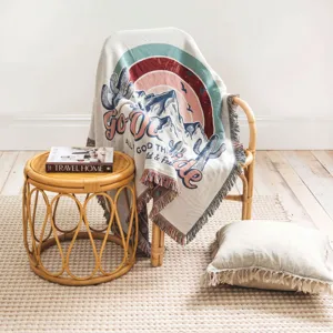 Boho-Wobbeldecke mit Wüstenlandschaft und 'Go Outside' Design auf einem Rattansessel.