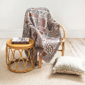 Detail of a bohemian woven throw blanket with fringe draped on a rattan chair