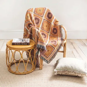 Bohemian woven throw blanket with floral pattern draped elegantly on a rattan armchair