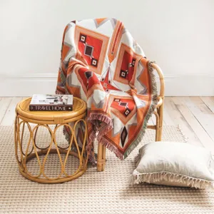 Bohemian geometric woven throw blanket with fringes draped on a natural rattan chair