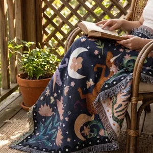 Couverture tissée bohème avec motifs fleurs et lune drapée sur une chaise en osier rustique