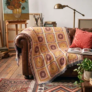 Close-up of a Bohemian woven sunflower throw blanket draped over a vintage leather sofa
