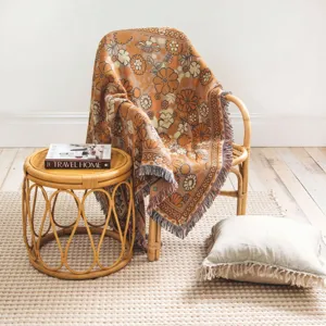 Bohemian retro floral throw blanket with tassels draped on a stylish rattan chair