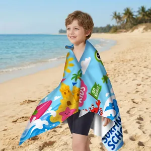 Junge in einem farbenfrohen Mikrofaser-Strandtuch mit Motiven am sonnigen Strand