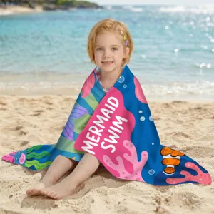 Kind in einem schnelltrocknenden Meerjungfrau-Strandtuch an einem sonnigen Strand