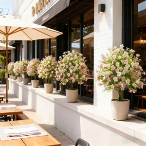 Rows of artificial pink and white potted flowers decorating a sunny outdoor cafe ledge