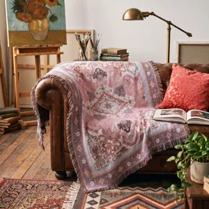 Artistic bohemian woven throw blanket with fringe displayed on a vintage leather sofa