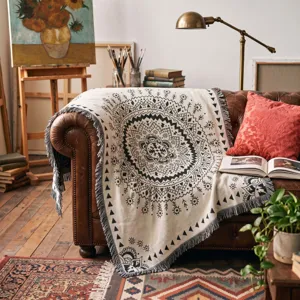 Artistic bohemian mandala throw blanket draped on a classic leather sofa in a studio