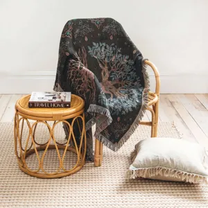 Bohemian woven blanket with tree of life pattern draped over a stylish rattan chair.
