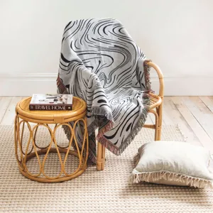 Vue détaillée d'un plaid tissé bohème à motif de marbre noir sur une chaise en rotin