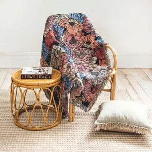 Detailansicht einer gewebten Boho-Blumendecke mit Fransen in wohnlicher Umgebung