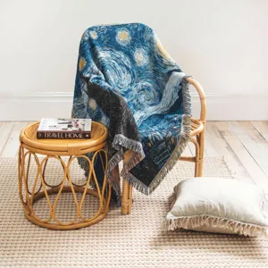 Couverture tissée avec motif Nuit étoilée de Van Gogh sur une chaise en rotin.