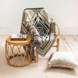 Bohemian tribal pattern woven throw blanket with fringes on a rattan chair.