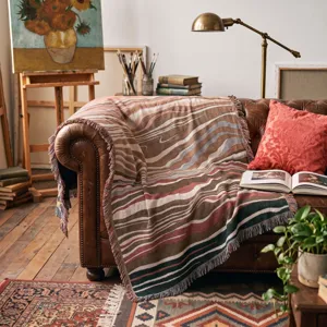 Detailed close-up of Bohemian style knit blanket with tassels on leather sofa