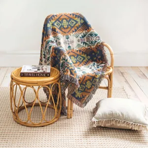 Manta de tejido bohemio con patrón geométrico sobre una silla de mimbre natural