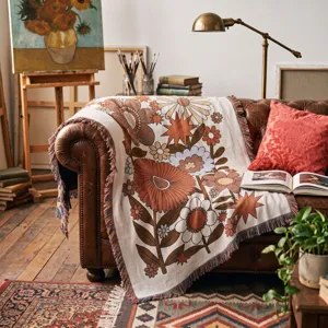 Retro bohemian floral woven throw blanket with fringes draped on a classic leather sofa